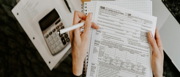 A person reviewing a U.S. tax form beside a calculator and notebook, illustrating family health insurance budgeting.