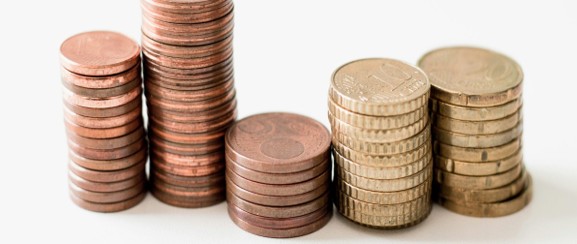 Stacks of coins at different heights, illustrating premiums, deductibles, and total health insurance costs.