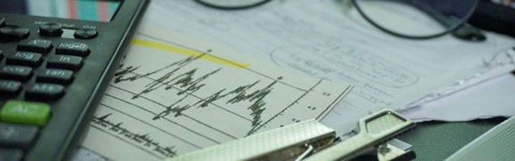 A calculator, eyeglasses, and financial paperwork arranged on a desk for policy comparison.