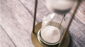 A close-up of sand passing through an hourglass on a wooden surface, representing a fixed coverage period.