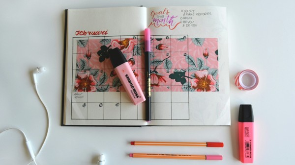 An open monthly calendar surrounded by pens and highlighters, illustrating a faster application timeline.